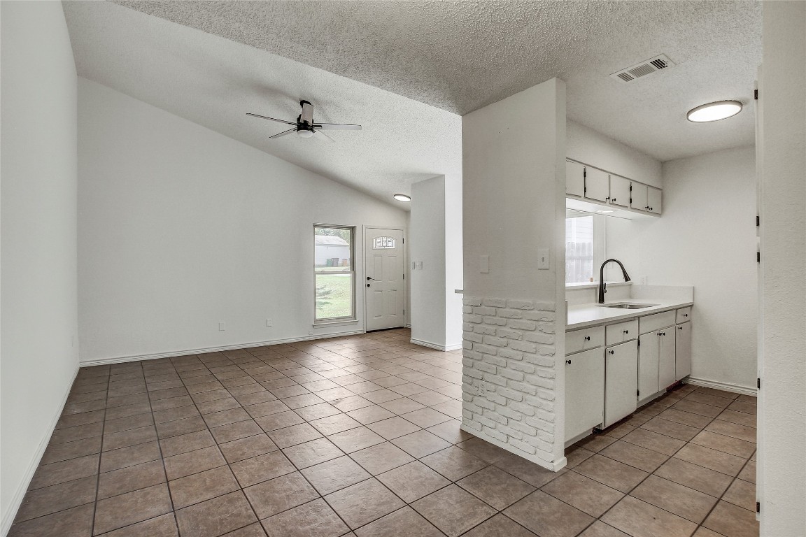 902 King Albert Street, Unit A Austin, TX 78745 - Photo 12 of 19 Kitchen featuring light countertops, light tile patterned flooring, a textured ceiling, white cabinets, and a ceiling fan