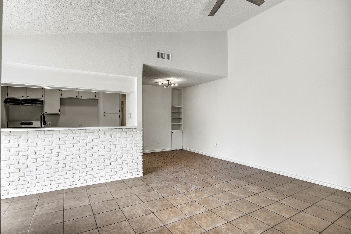 902 King Albert Street, Unit A Austin, TX 78745 - Photo 4 of 19 Unfurnished living room with vaulted ceiling, a textured ceiling, a ceiling fan, and tile patterned flooring
