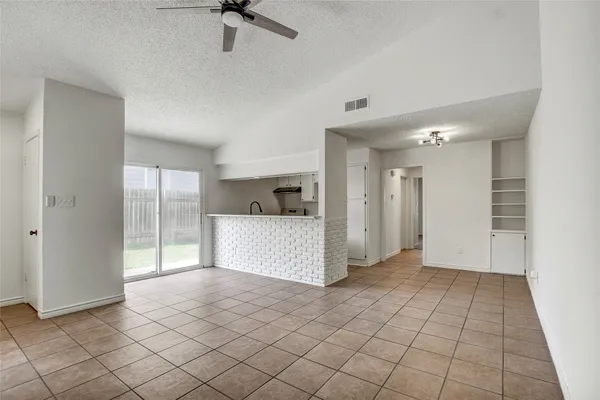 a view of a refrigerator in kitchen and an empty room
