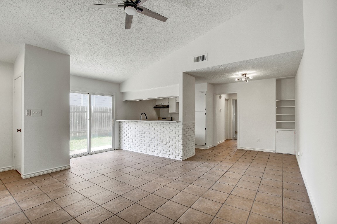 902 King Albert Street, Unit A Austin, TX 78745 - Photo 6 of 19 Unfurnished living room with a textured ceiling, light tile patterned flooring, ceiling fan, and high vaulted ceiling