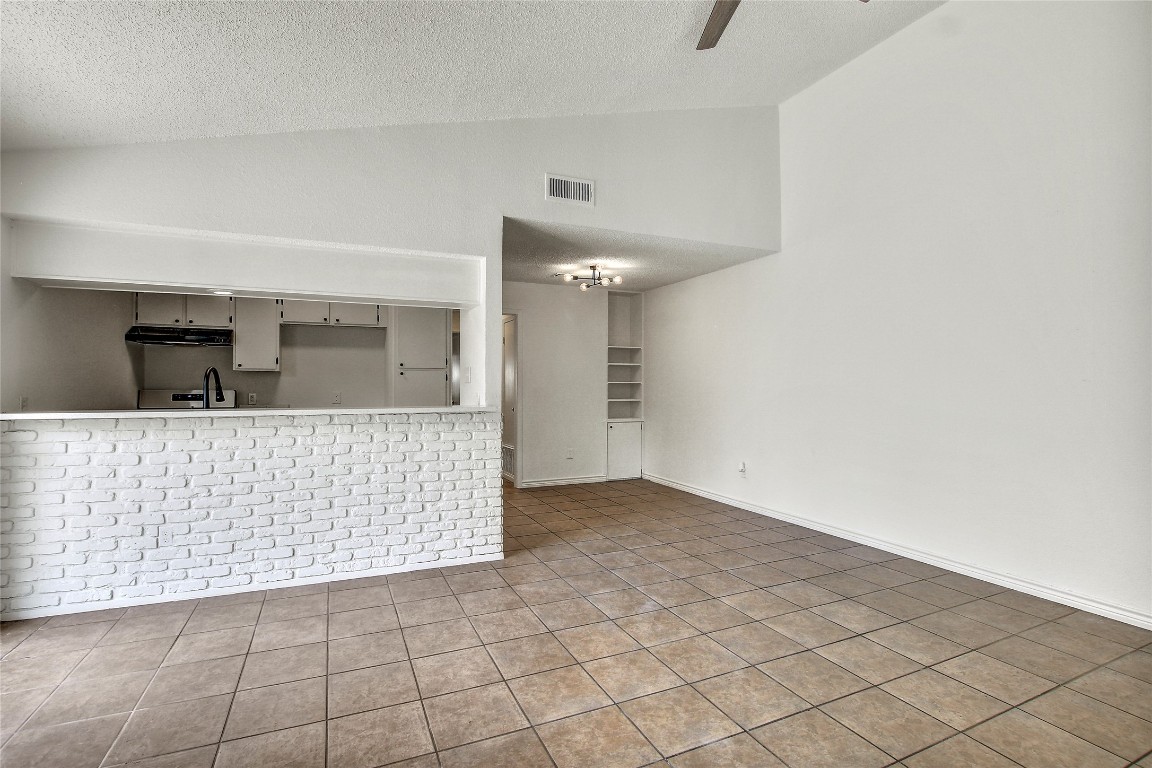 902 King Albert Street, Unit A Austin, TX 78745 - Photo 7 of 19 Unfurnished living room featuring lofted ceiling, a textured ceiling, ceiling fan, and tile patterned floors