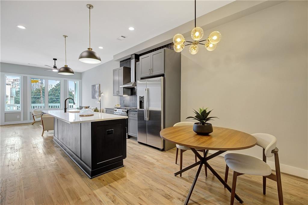 454 Connally Street Southeast Atlanta, GA 30312 - Photo 8 of 32 a kitchen with stainless steel appliances granite countertop a refrigerator a sink dishwasher a dining table and chairs with wooden floor