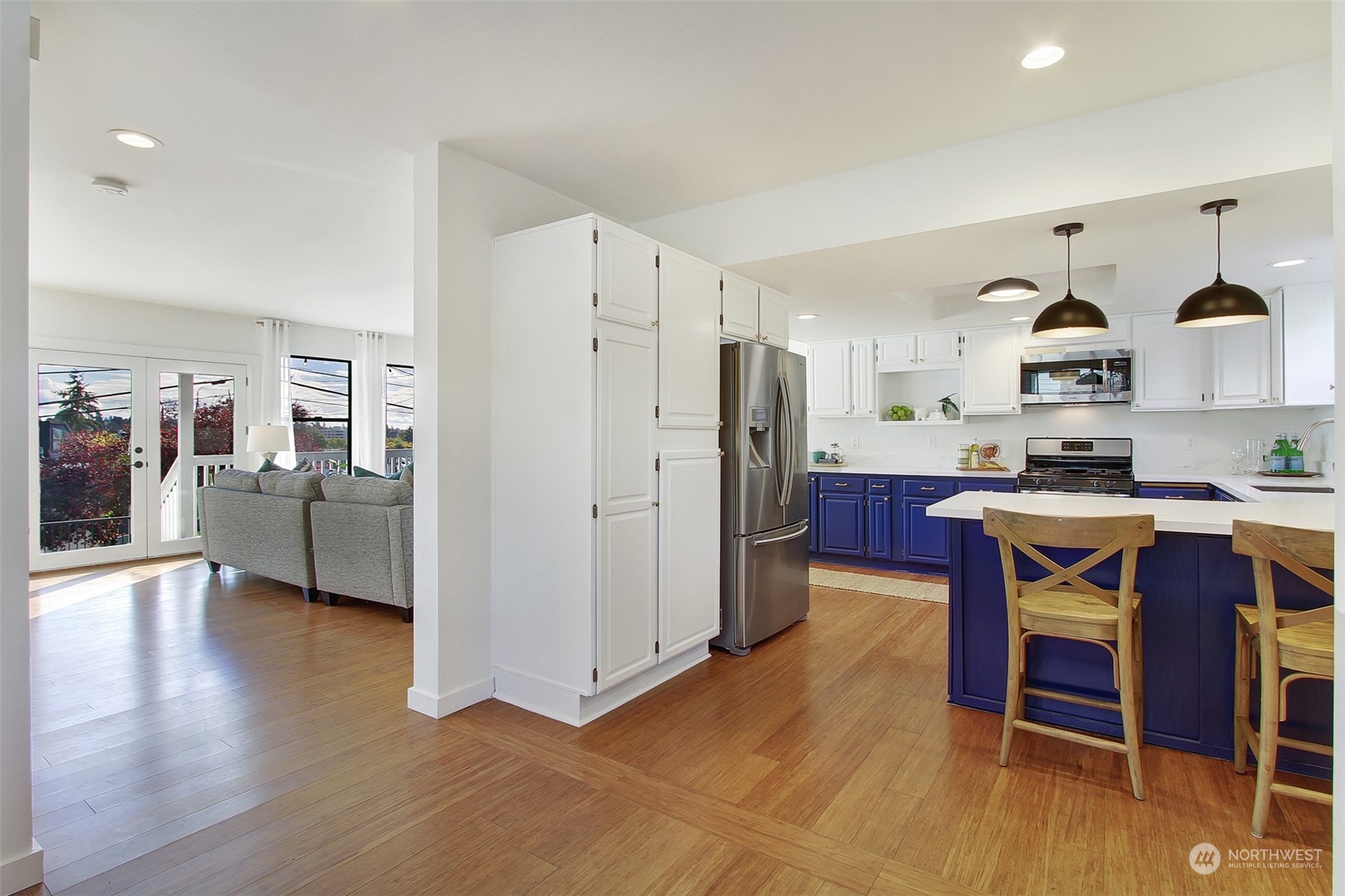 323 Northeast 76th Street Seattle, WA 98115 - Photo 9 of 33 a kitchen with stainless steel appliances kitchen island granite countertop a refrigerator a stove and white cabinets with wooden floor