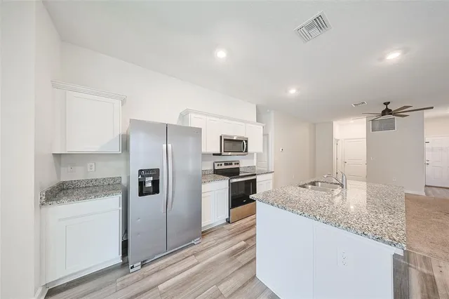 a kitchen with granite countertop kitchen island wooden cabinets and stainless steel appliances