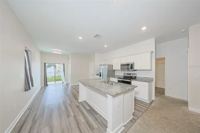 a kitchen with granite countertop a stove top oven a sink dishwasher and a refrigerator