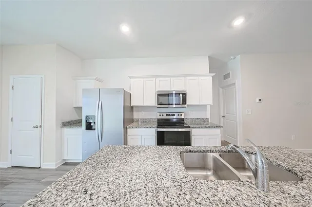 a kitchen with stainless steel appliances granite countertop a refrigerator stove and sink