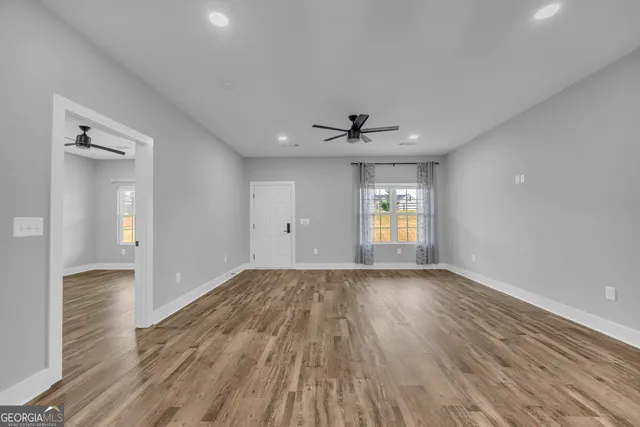 a view of empty room with wooden floor and fan