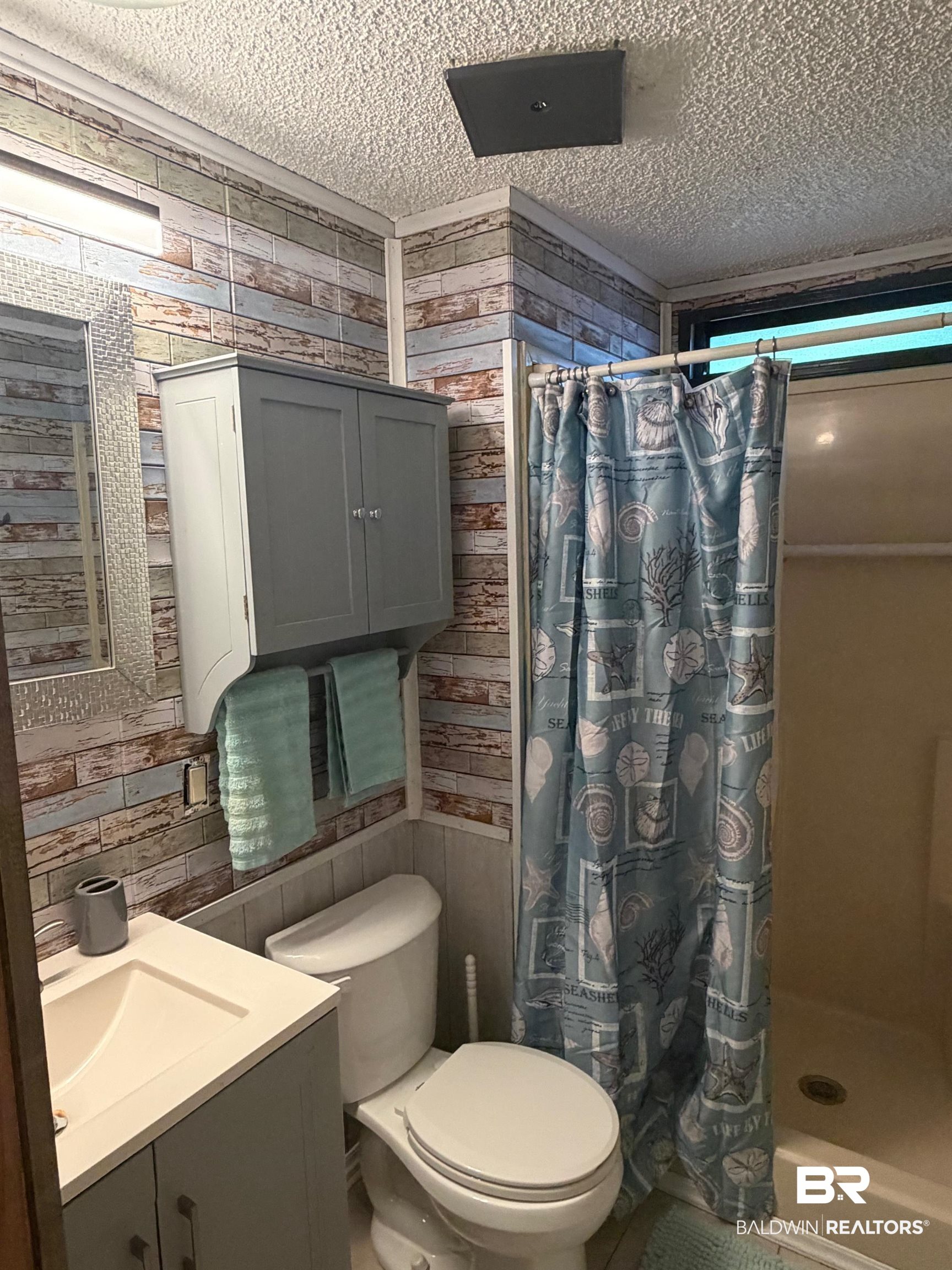1127 Ridgewood Drive Lillian, AL 36549 - Photo 10 of 32 Bathroom with a shower stall, vanity, a textured ceiling, and wooden walls