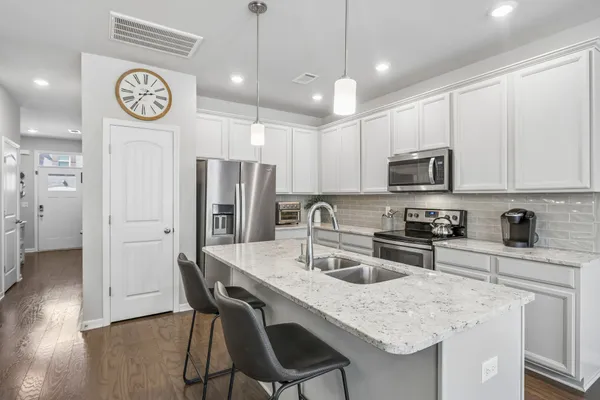 a kitchen with granite countertop a table chairs stove refrigerator and cabinets