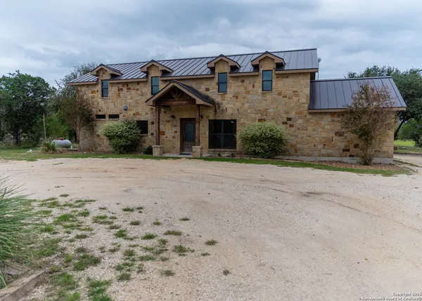 a kitchen with stainless steel appliances kitchen island granite countertop a dining table chairs refrigerator and sink