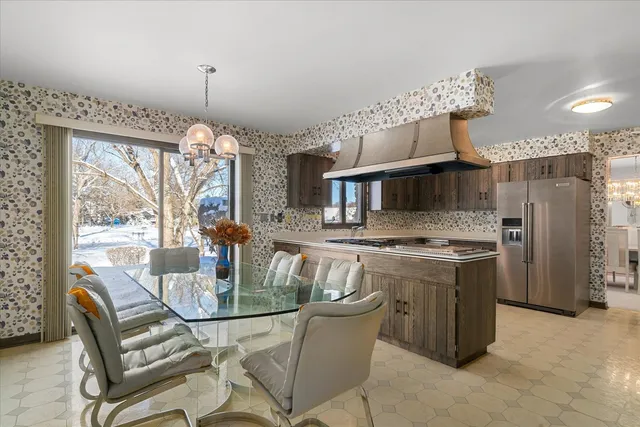 a kitchen with stainless steel appliances granite countertop a stove a refrigerator a kitchen island a dining table and chairs