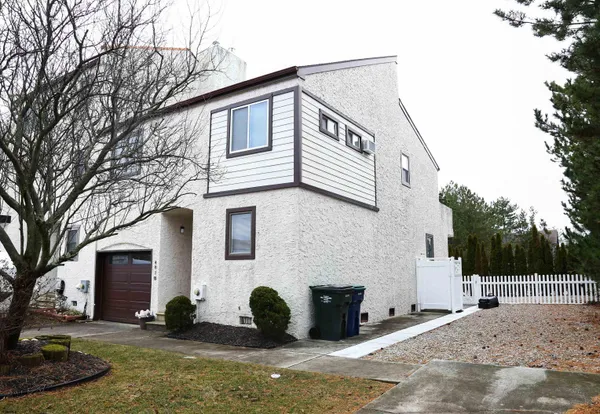 a view of a white house with a large tree
