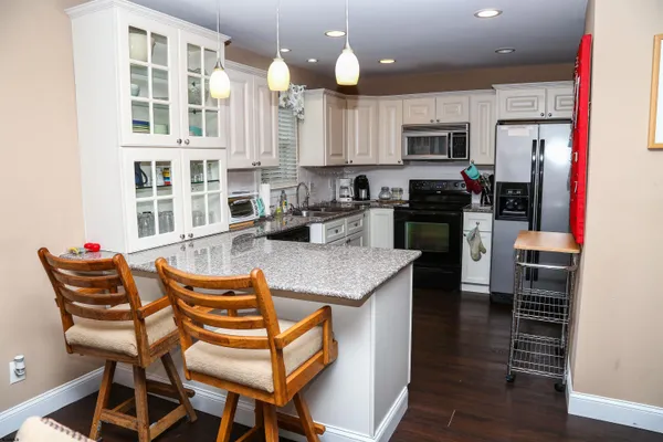 a kitchen with stainless steel appliances granite countertop a stove top oven a sink a dining table and chairs