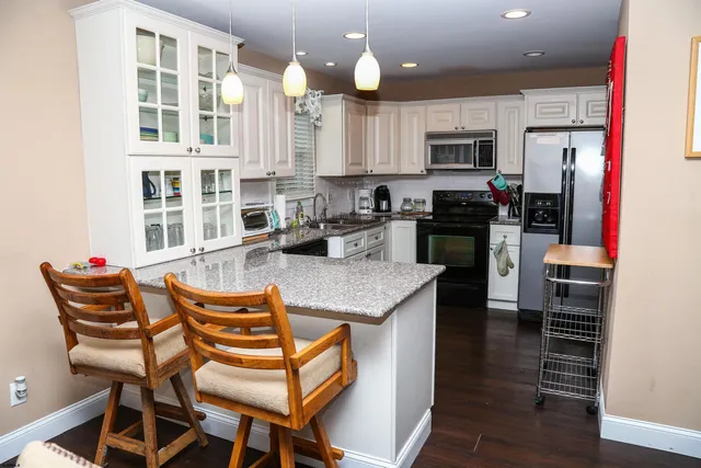 a kitchen with stainless steel appliances granite countertop a stove top oven a sink a dining table and chairs