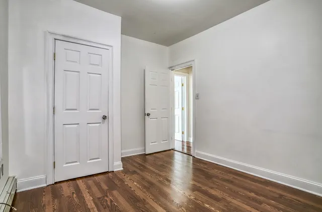 a view of an empty room with closet and wooden floor