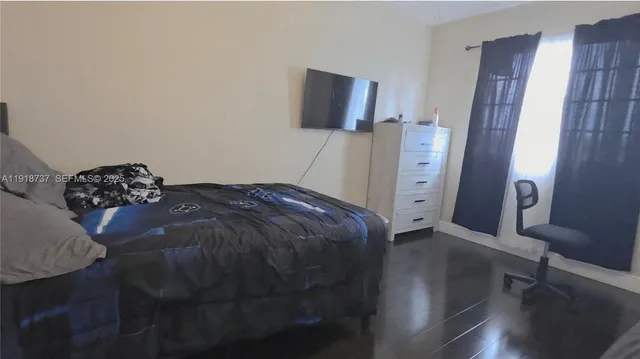 a bed sitting in a bedroom next to a window with chair and table