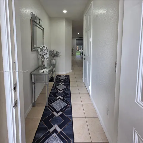 a hallway with white doors wooden floor and black chairs