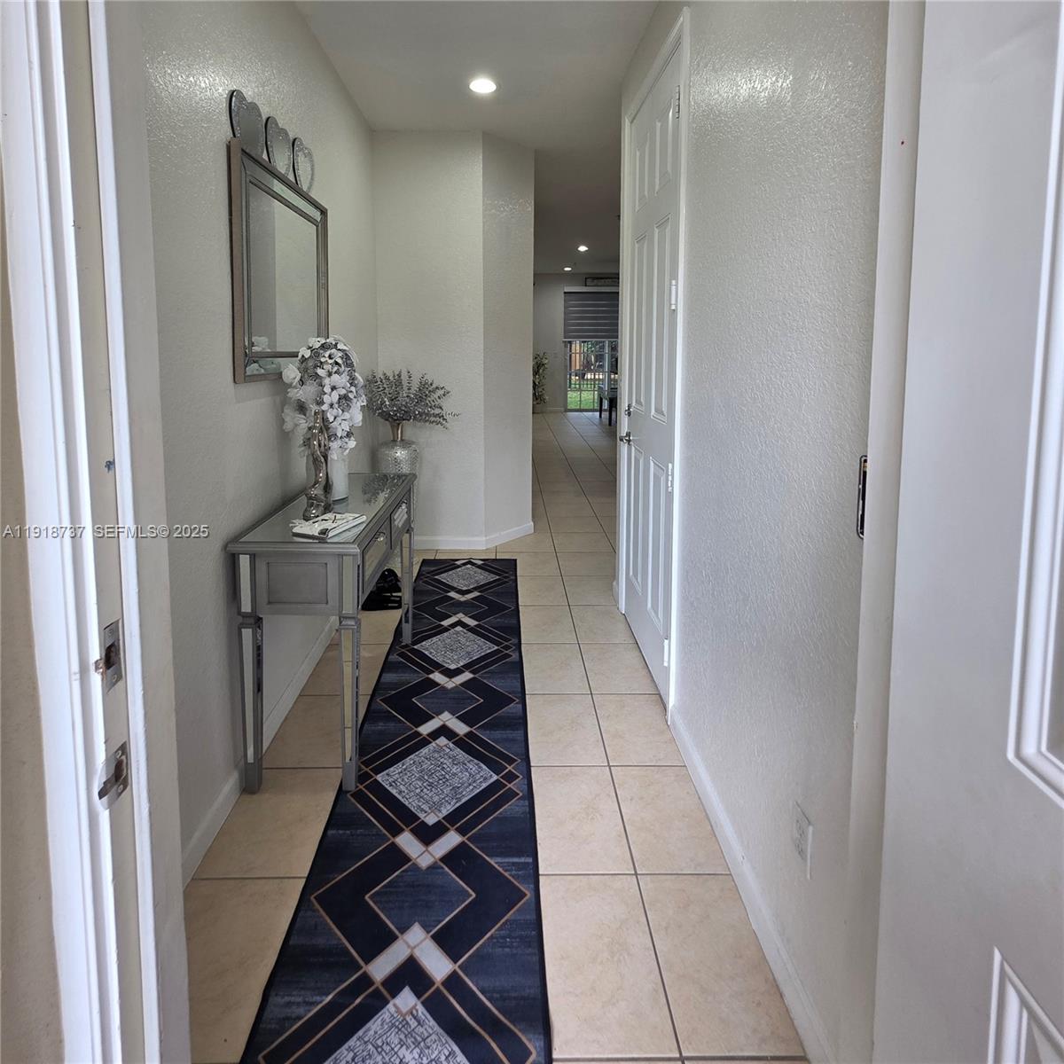 2612 Southwest 81st Terrace, Unit 206 Miramar, FL 33025 - Photo 4 of 40 a hallway with white doors wooden floor and black chairs