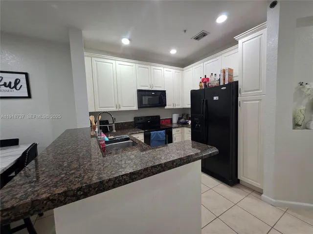 a kitchen with granite countertop a refrigerator and a sink