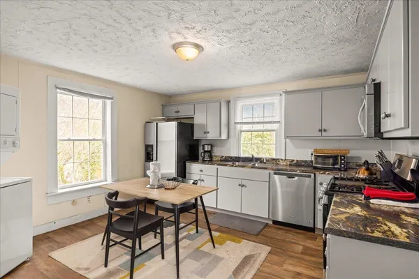 a kitchen with stainless steel appliances granite countertop a stove top oven a sink dishwasher and cabinets with wooden floor