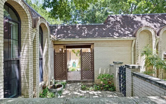 a view of a brick house with large windows and plants