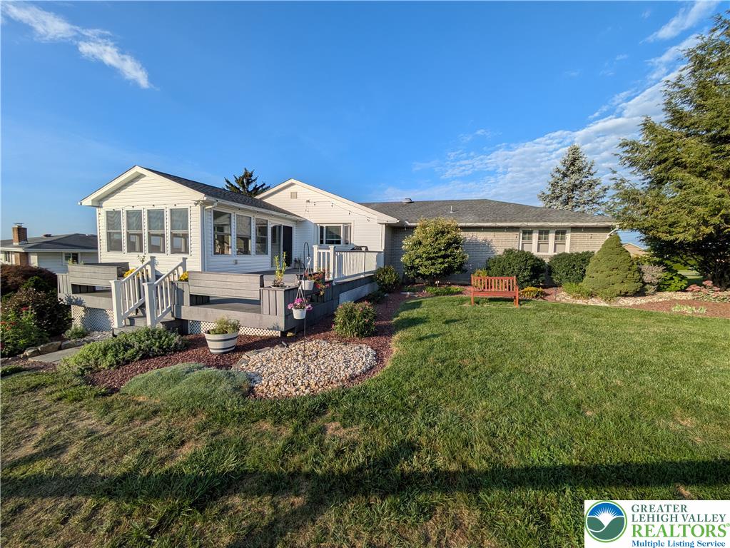 3285 Cherryville Road Northampton, PA 18067 - Photo 45 of 51 An expansive backyard lawn wraps around a raised wooden deck and sunroom.