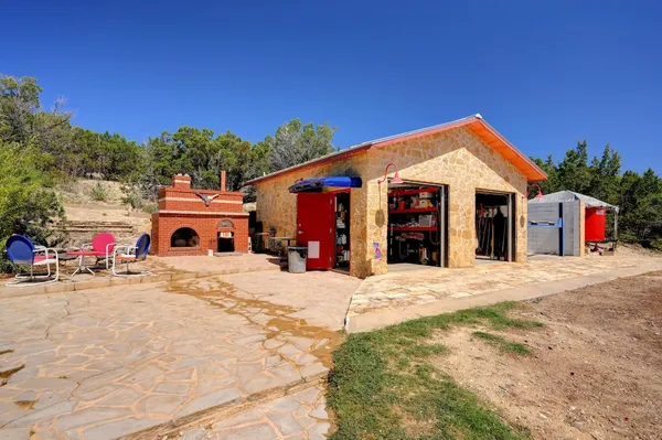 a view of house with outdoor seating and trees in the background