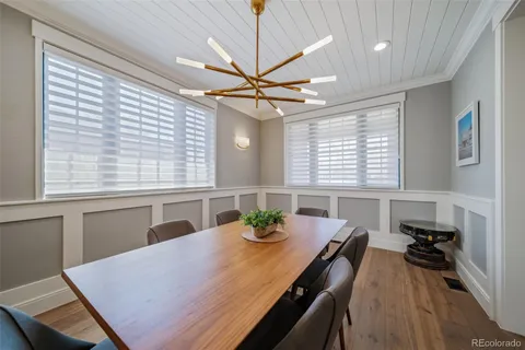 a dining room with wooden floor a chandelier a wooden table and chairs