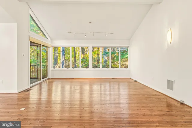 an empty room with wooden floor and windows