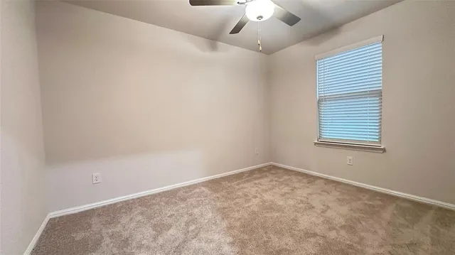 an empty room with a ceiling fan and carpet