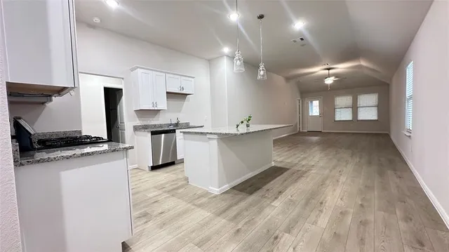 a view of a kitchen with kitchen island a sink wooden floor and a large window