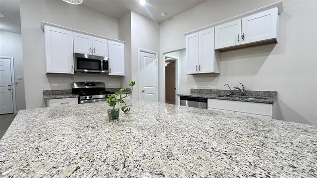 a kitchen with stainless steel appliances granite countertop a stove top oven a sink dishwasher and a microwave oven with the cabinets