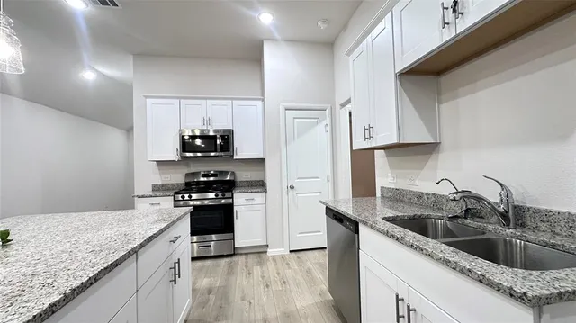 an empty room with a chandelier fan and windows