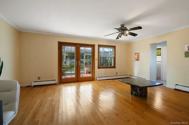 a view of empty room with wooden floor and fan