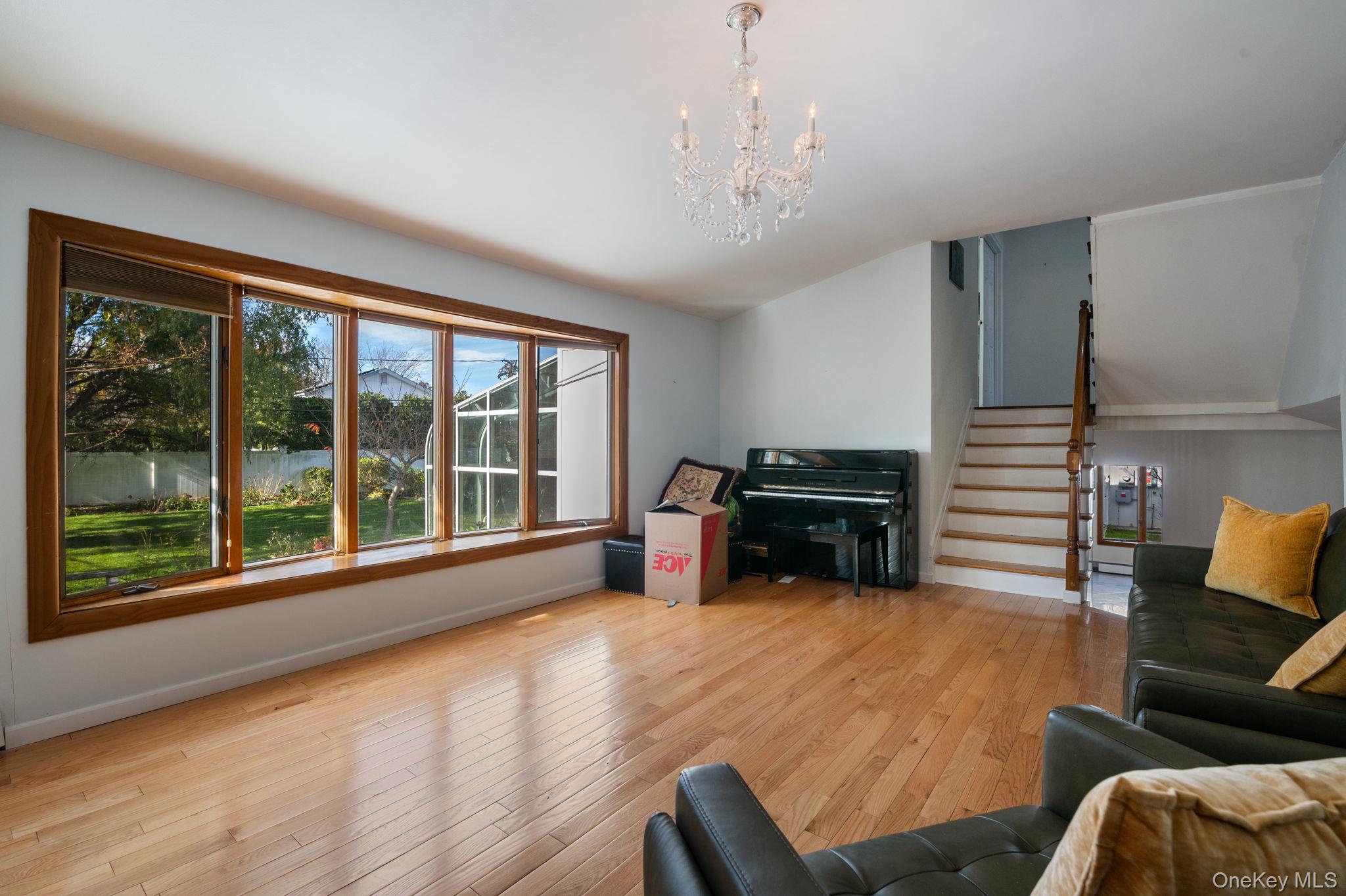 89 Nottingham Road Manhasset Hills, NY 11040 - Photo 16 of 39 Living room featuring light wood finished floors, stairway, and a chandelier