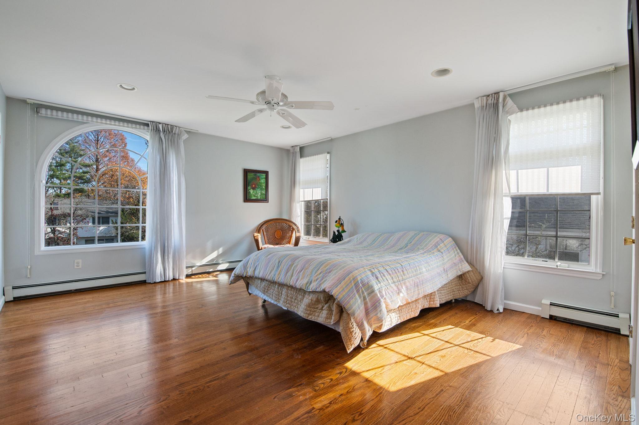 89 Nottingham Road Manhasset Hills, NY 11040 - Photo 27 of 44 a spacious bedroom with a bed a dresser and wooden floor