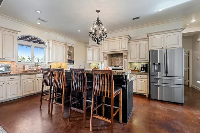 a kitchen with stainless steel appliances a refrigerator a stove a sink dishwasher and a dining table with wooden floor