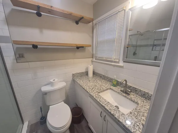 a bathroom with a granite countertop toilet sink and mirror