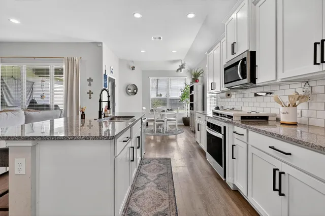 a large kitchen with stainless steel appliances granite countertop a lot of counter space and wooden floor