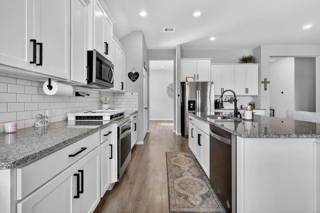 a large kitchen with stainless steel appliances granite countertop a lot of counter space and a sink