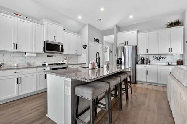a kitchen with stainless steel appliances granite countertop a table chairs microwave and refrigerator