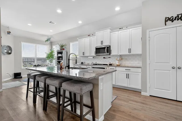 a kitchen with white cabinets stainless steel appliances and dining table