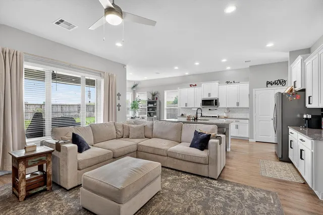 a living room with furniture and a large window with kitchen view