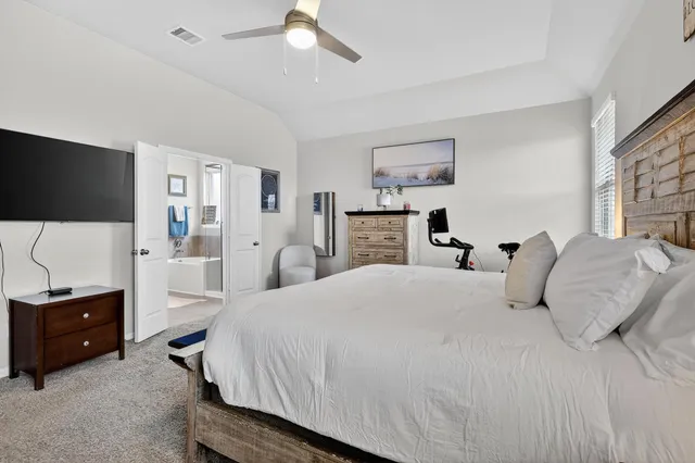 a bedroom with a bed and a flat tv screen on dresser
