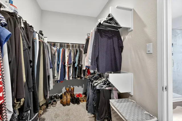 a view of walk in closet with clothes and shoes