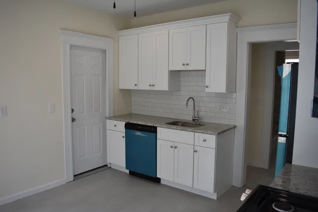 a kitchen with granite countertop white cabinets and sink
