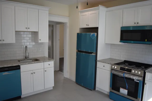 a kitchen with white cabinets and stainless steel appliances