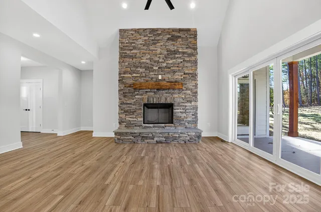 an empty room with wooden floor fireplace and windows