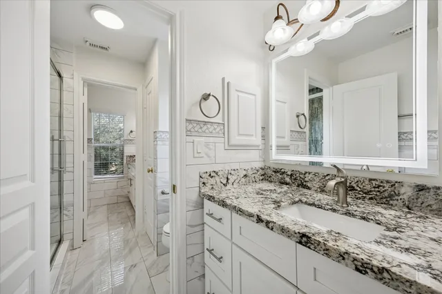 a bathroom with a granite countertop sink a large mirror and a shower