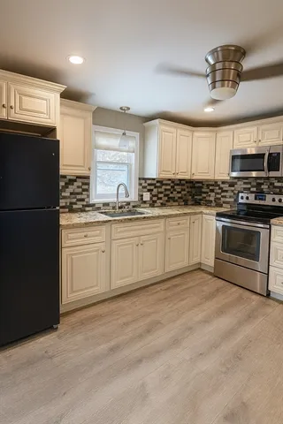 a kitchen with stainless steel appliances granite countertop a stove a sink and a refrigerator